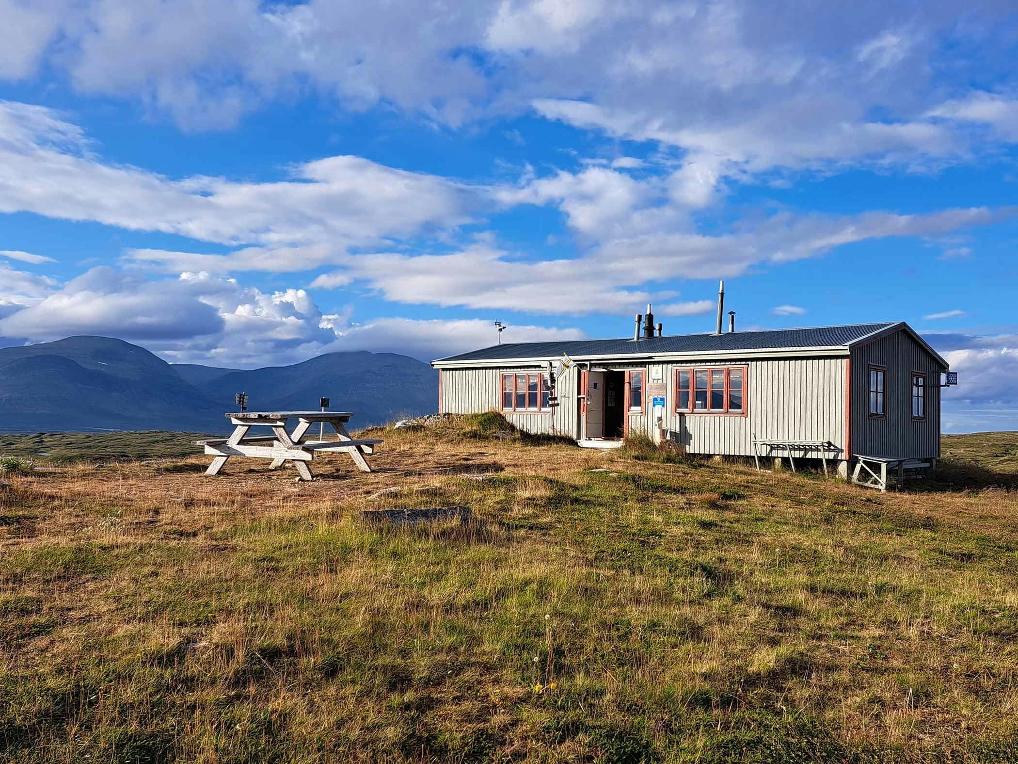 Mountain cabin in open mountain landscape with views of mighty mountains in the background.