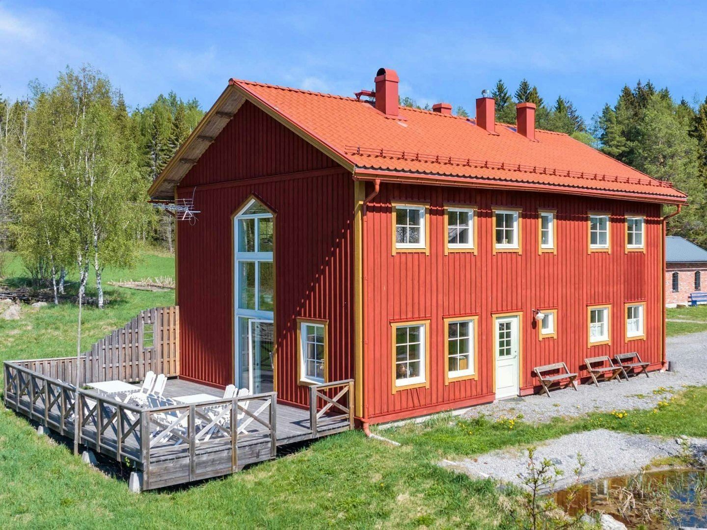 Rött trähus med uteplats i lantlig grönskande miljö.