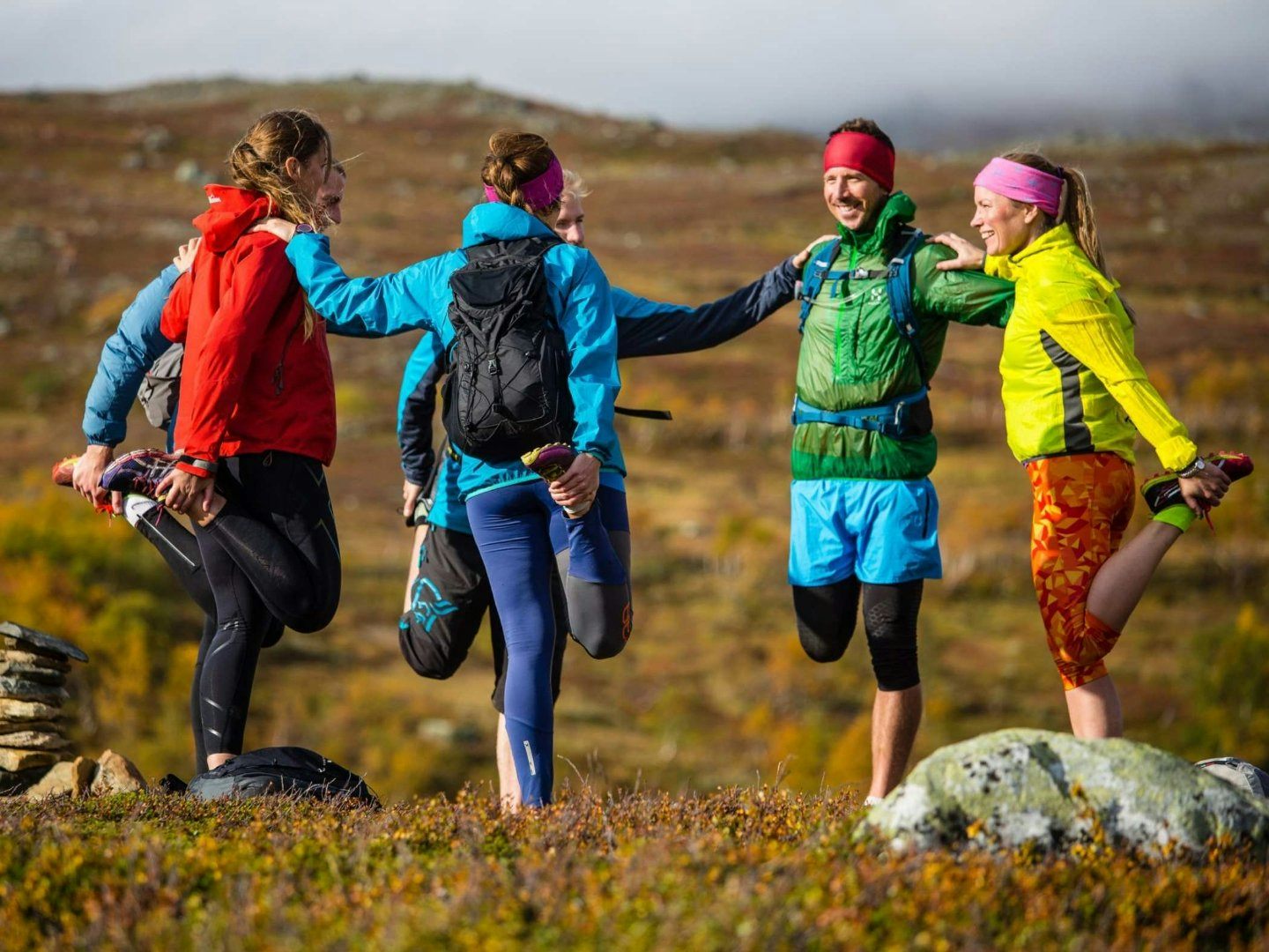 Fyra personer stretchar tillsammans i ett fjällandskap.