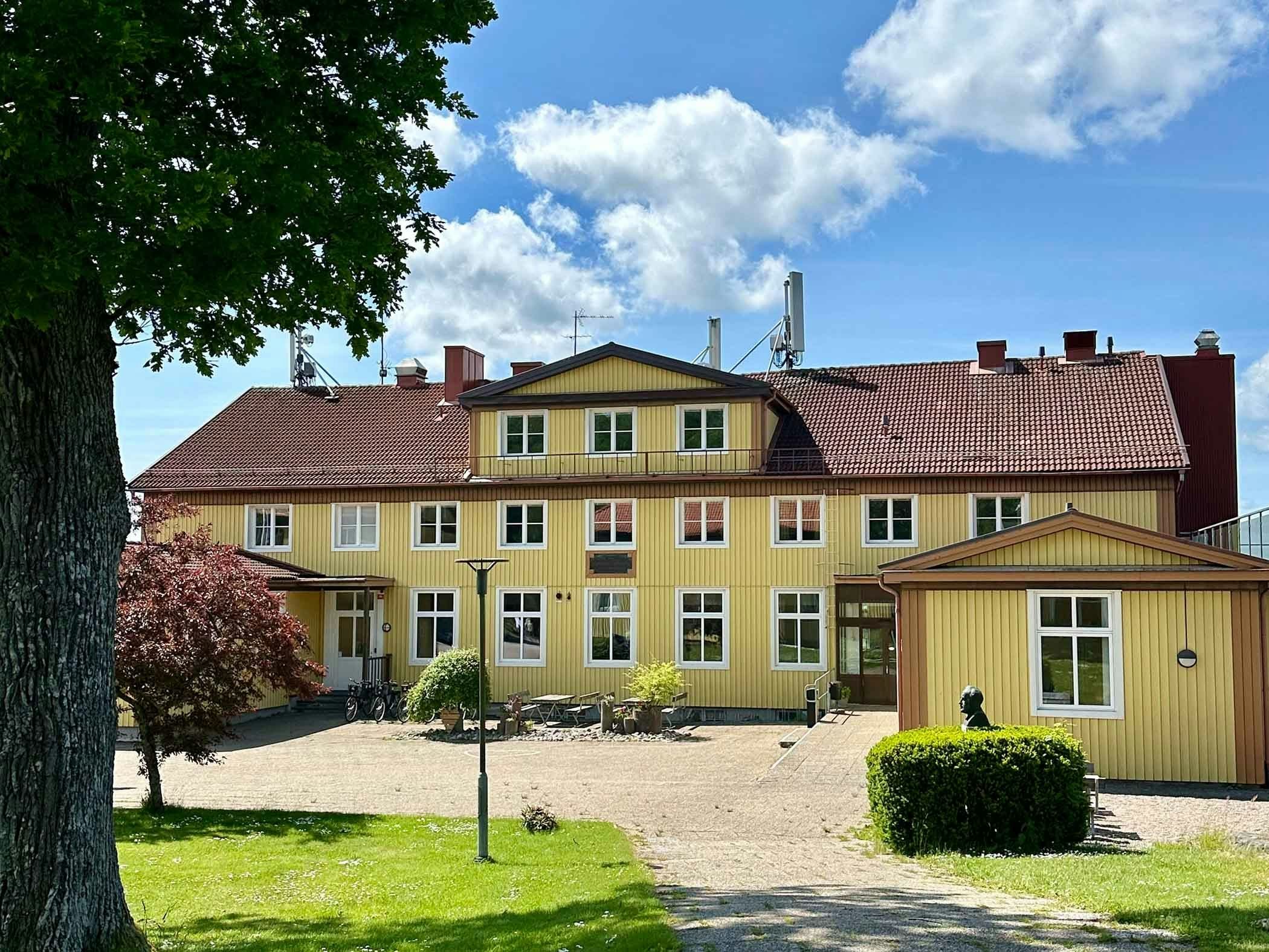 Lush small town by the water, with a boat harbor and archipelago islands in the background.