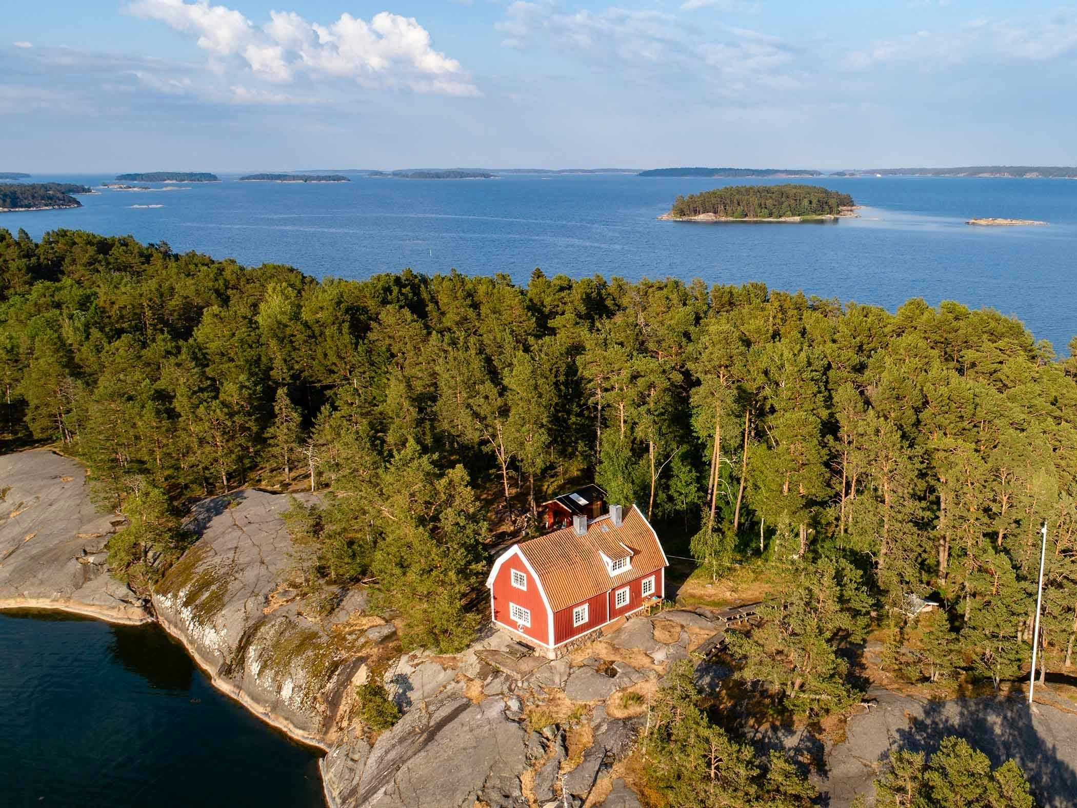 Red cottage by the water surrounded by forest on an island in the archipelago.