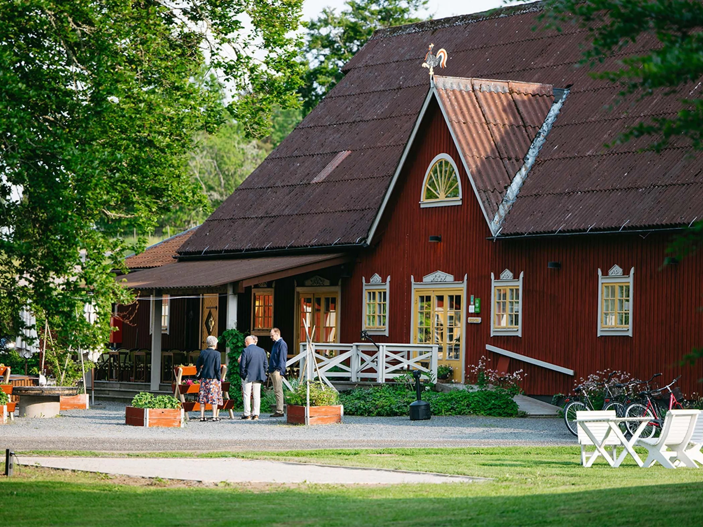Gäster utanför Wallby Säteri Gårdshotells röda huvudbyggnad.