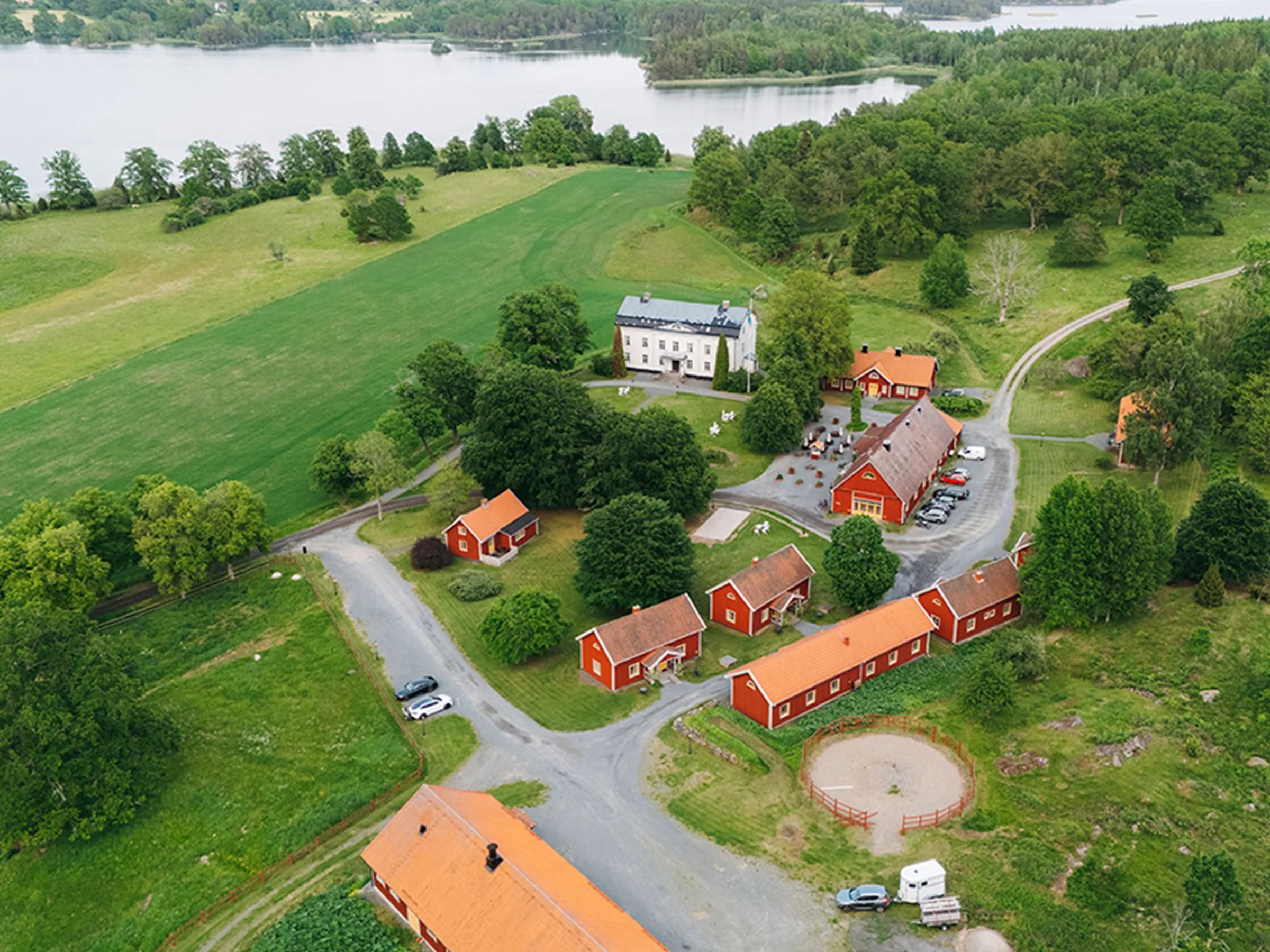 Flygbild över Wallby Säteri Gårdshotell vid sjön.