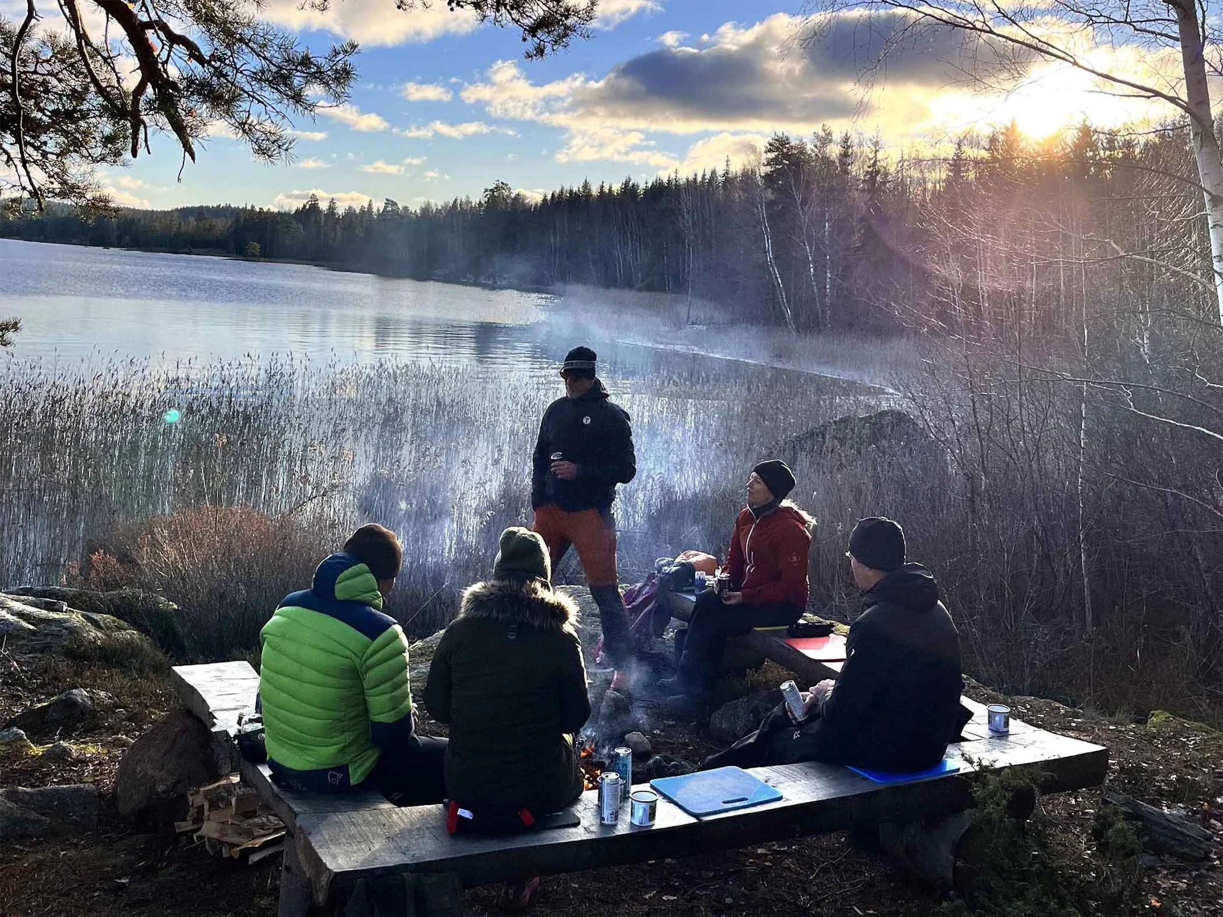 Sällskap vid en lägereld på en sjöstrand.