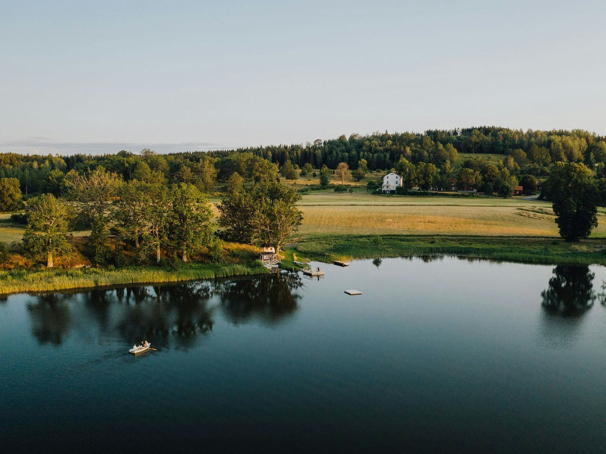 Stilla sjö omgiven av skog och åkrar.