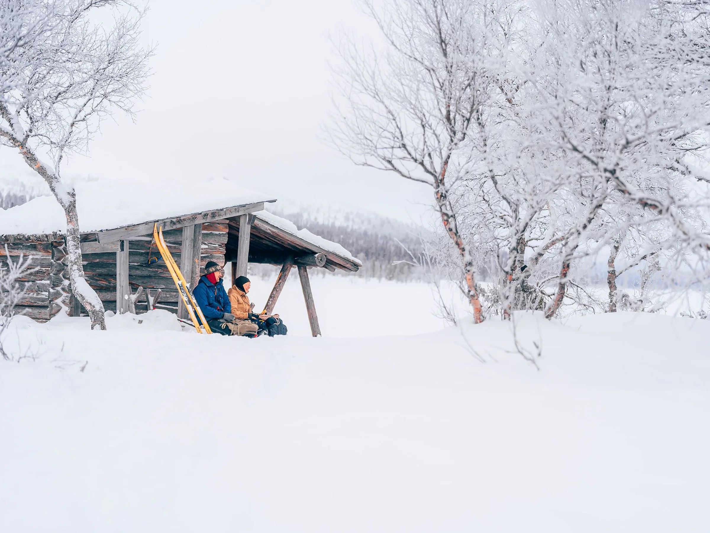 Person resting in a lean-to in the snow.