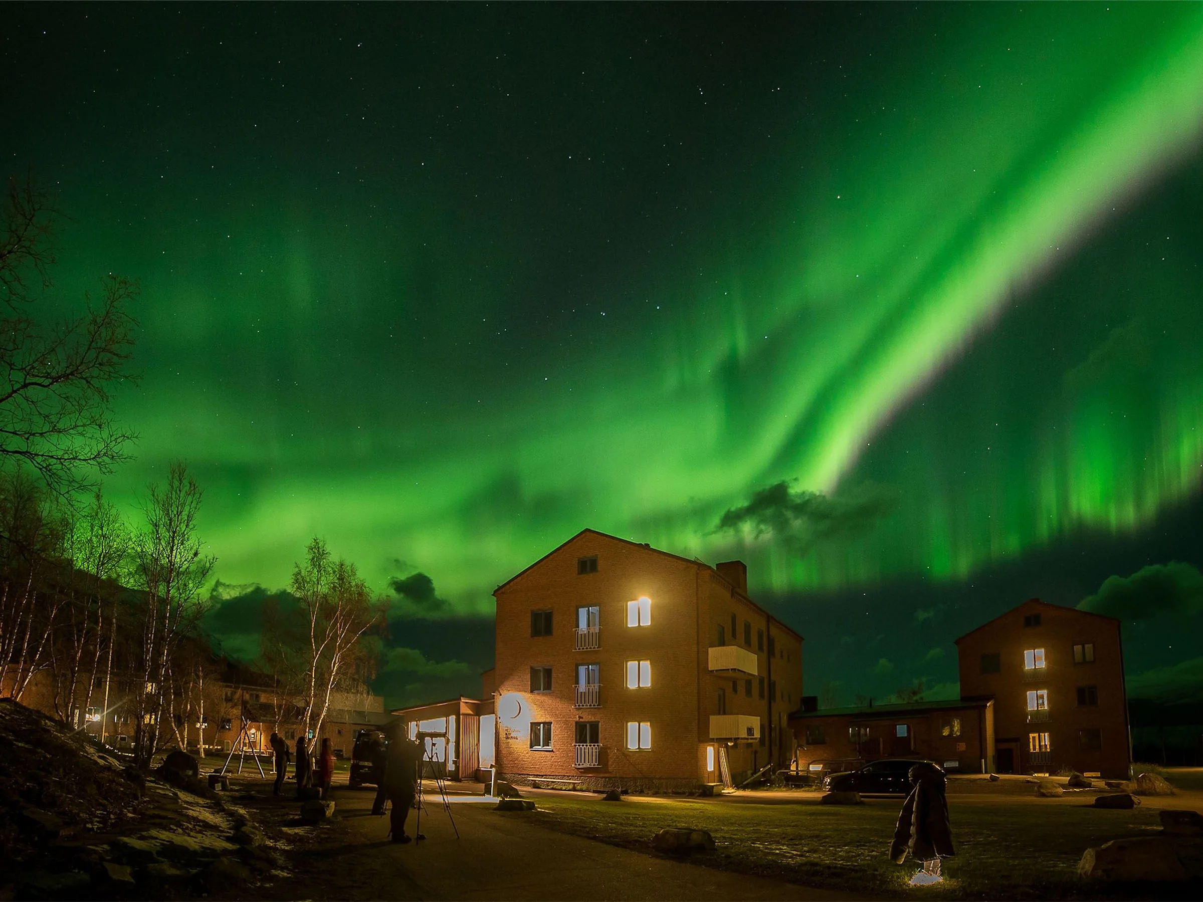 STF Abisko Turiststation med vatten i förgrunden.