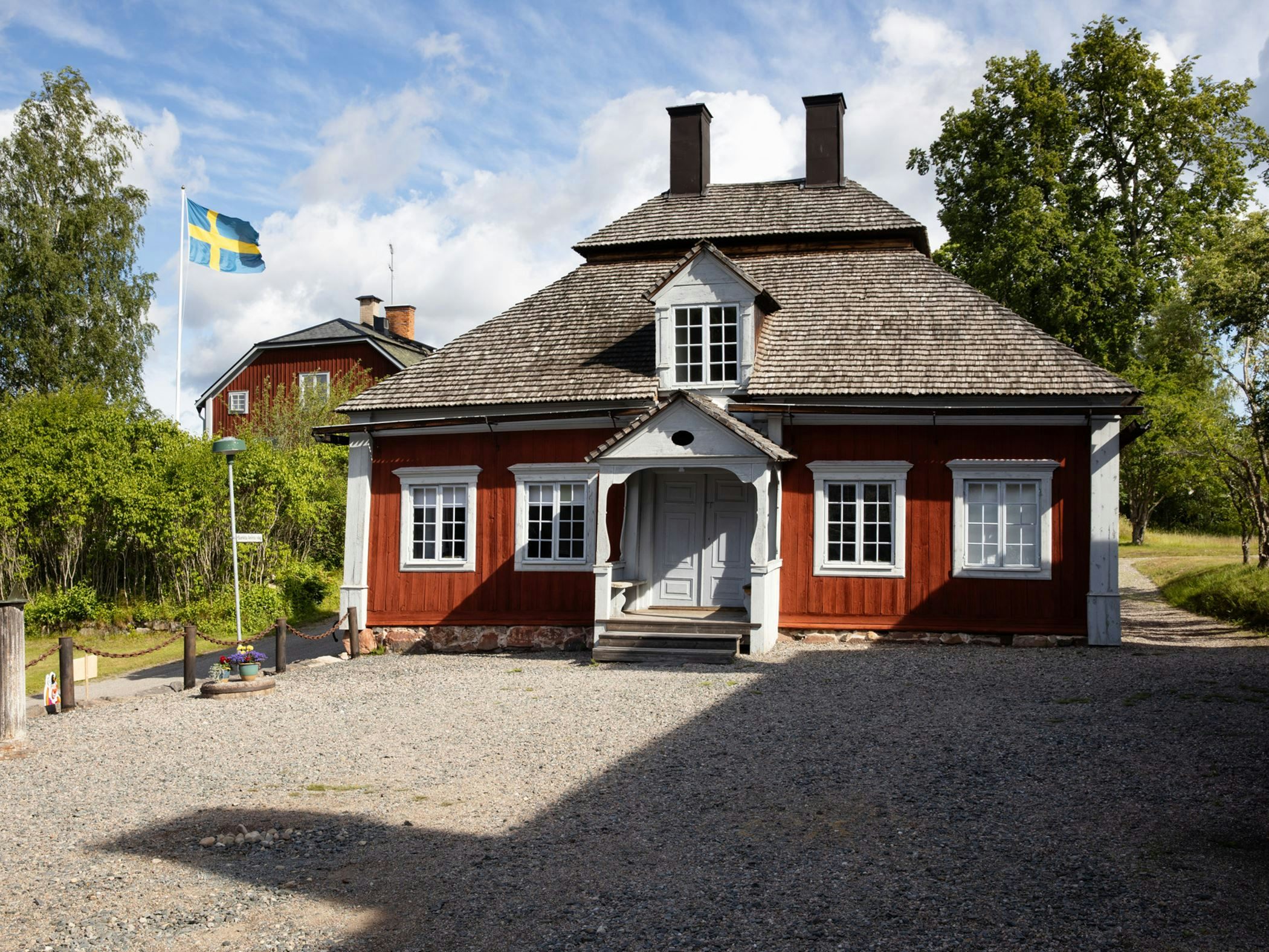 Classic rustic red timber building with distinctive roof architecture and Swedish flag - historic and homely feel.