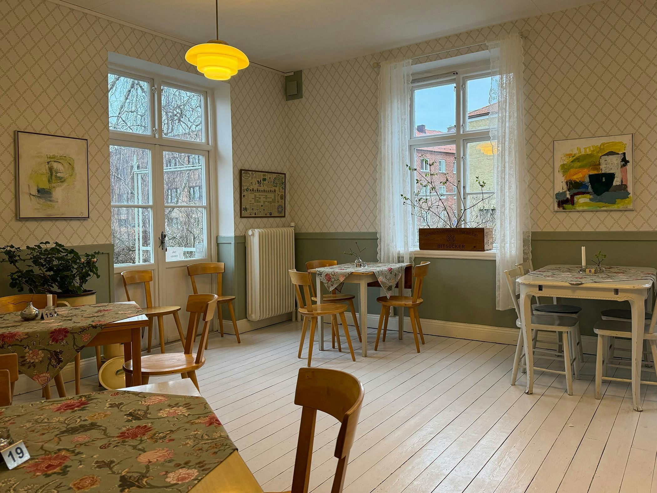 Bright and homely café with floral tablecloths, classic wooden chairs and large windows that let in daylight.